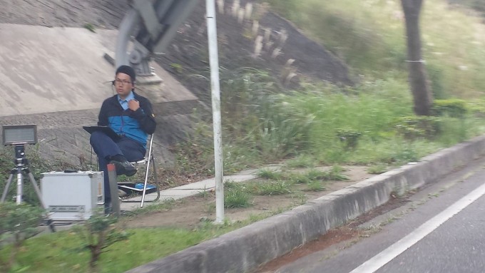 ここまで近づくと分かりますが、ここでレーダーに気付いたって「時既に遅し！」です。無線で「はい“わ”ナンバーの白のカローラ」とこの先に控えている取り締まり軍団に伝えられ、手持ちの「止まれ」の旗に止められて、あえなく御用となる訳です。