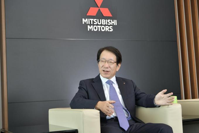 三菱自動車のロゴをバックにした加藤隆雄CEOのインタビュー