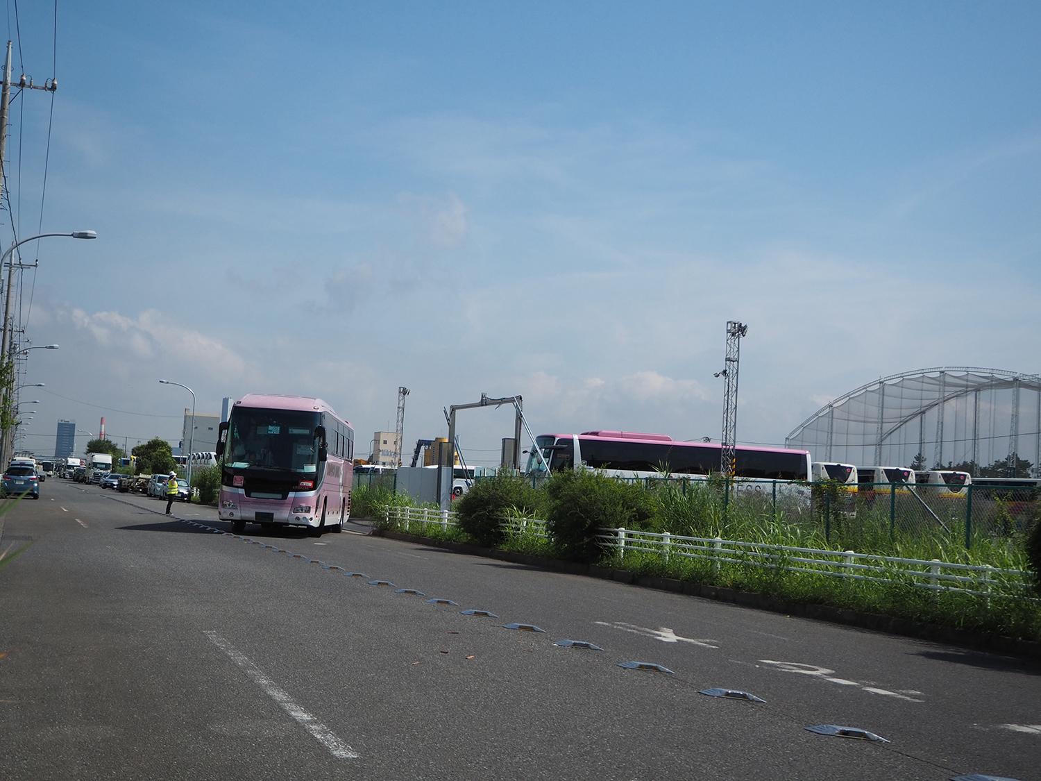デポから出発するオリンピック関係者輸送用に手配された地方の観光バス