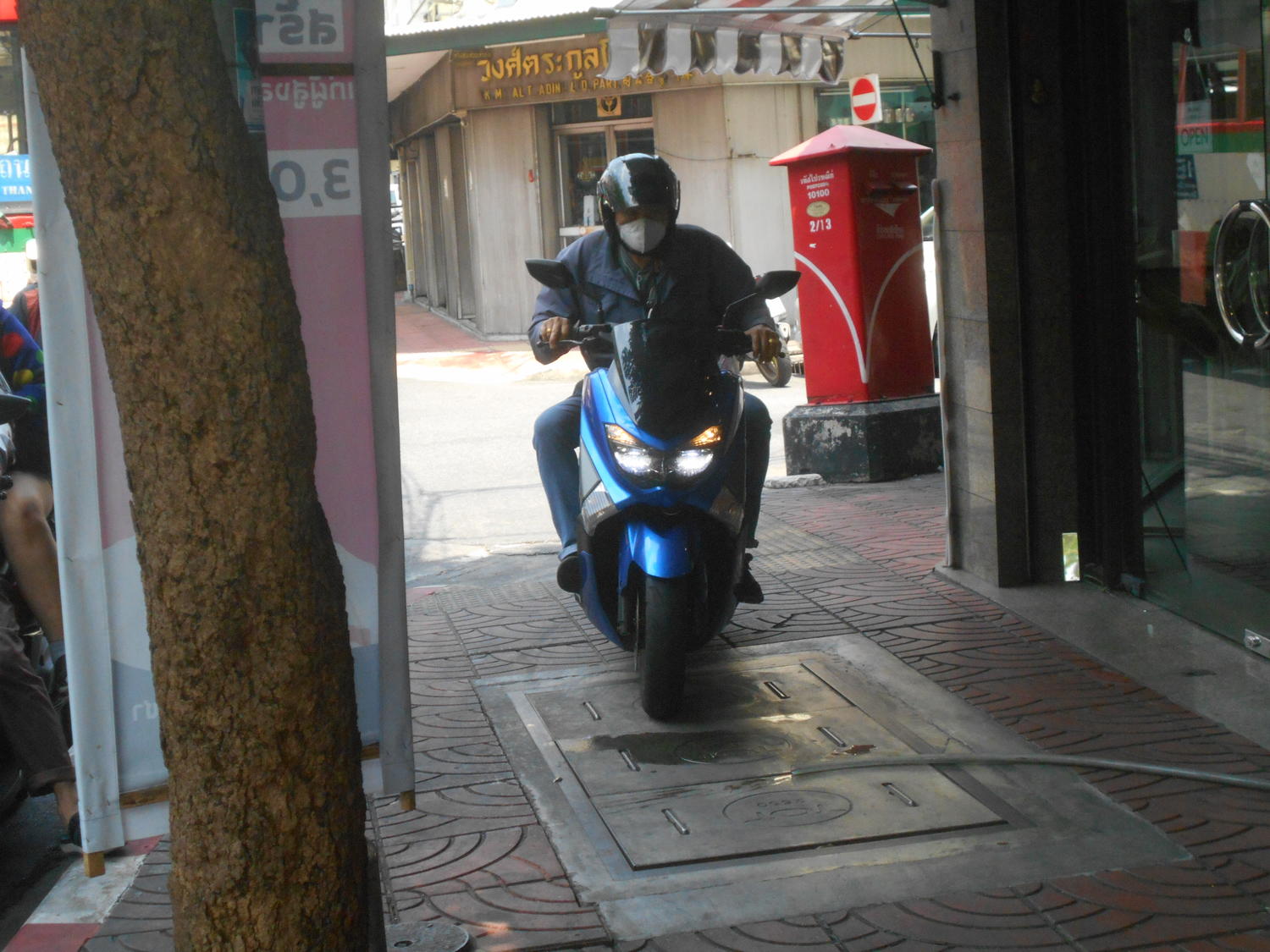 バンコク市内の歩道を走行するスクーターの写真 〜 画像1
