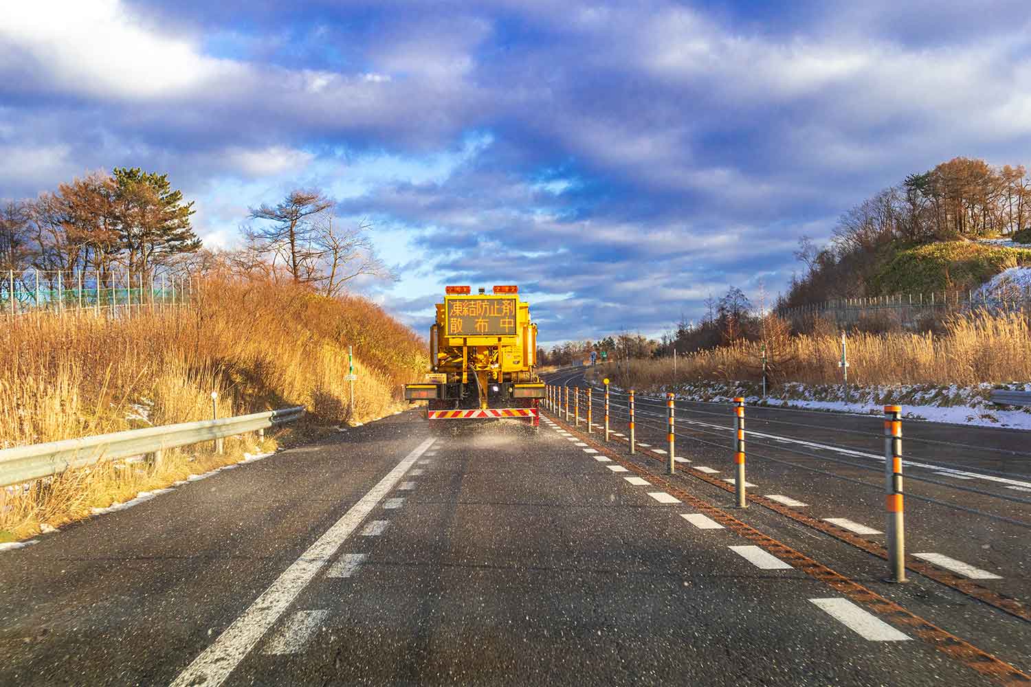 作業車が凍結防止剤を道路上に撒いている写真