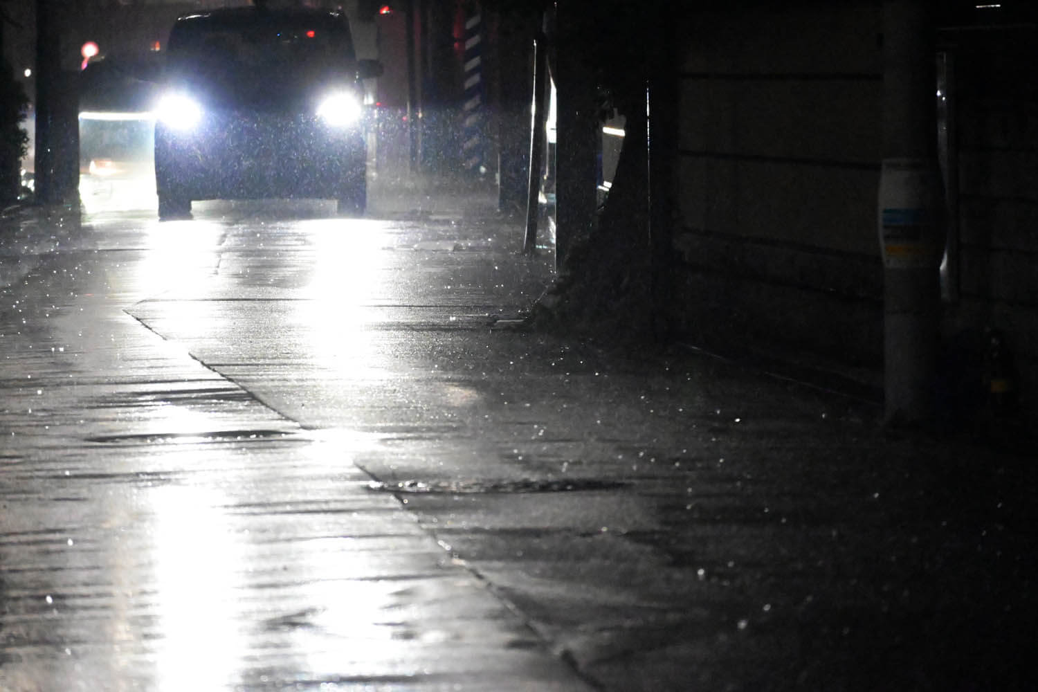 雨降る夜間に街灯のない車道を走行するクルマ